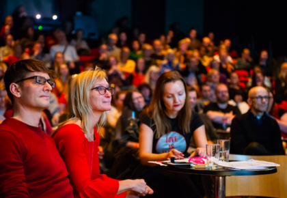 Publikum i Wergelandssalen med frivillig Andy Bennett, festivalsjef Kjersti Helgeland og medarrangør Marianne Støle-Nilsen i forgrunnen
